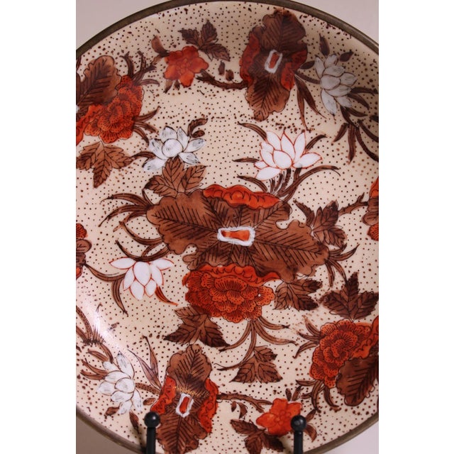 Decorative porcelain platter with warm gold-toned rim and signed maker mark on the underside. A refined display plate for...