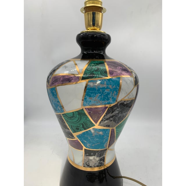 Handcrafted table lamp with a glossy black glazed ceramic base, featuring a classic vase shape with a sinuous profile and...