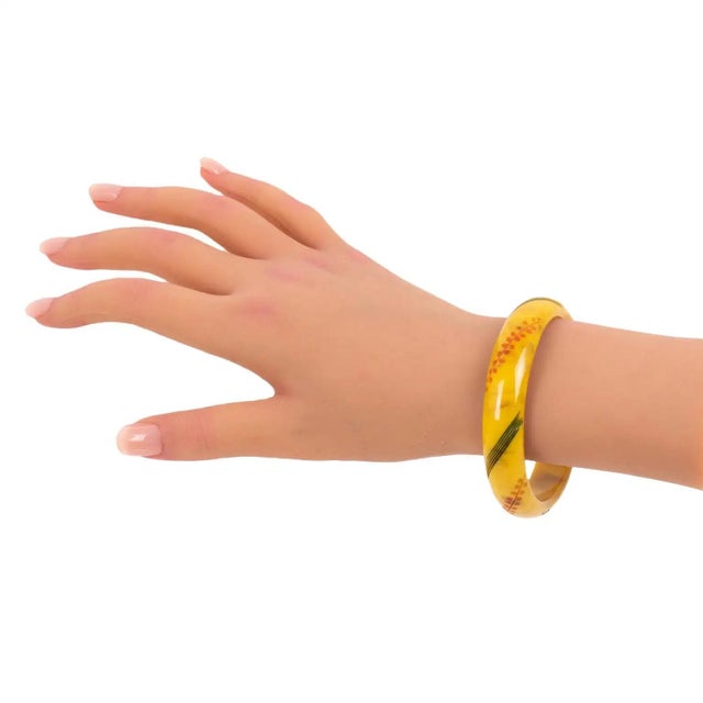 This stunning Bakelite bracelet bangle features a chunky domed shape with stylized floral and geometric carving, all...