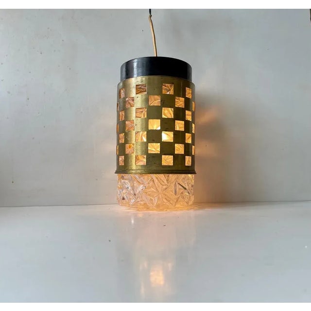 Midcentury modern German hanging light composed of pressed glass featuring a solid brass outer-shade with quadratic...