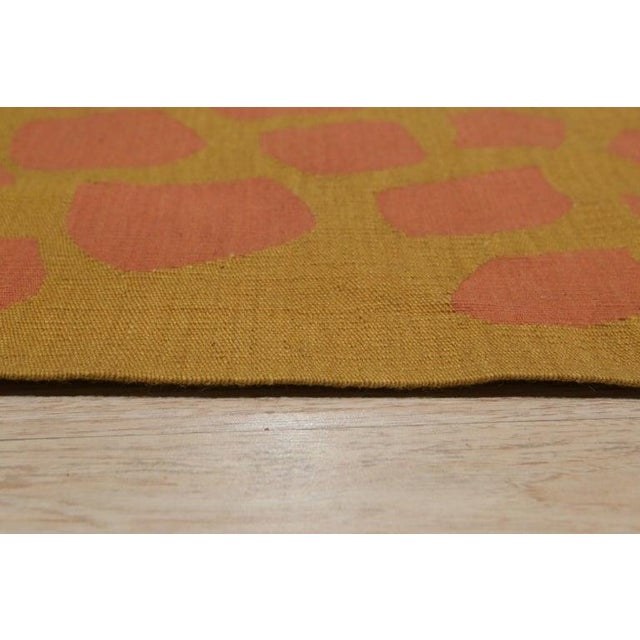 This wool rug measures 6 x 8 feet and features a primary color palette of coral, salmon, and pink tones. Constructed as a...