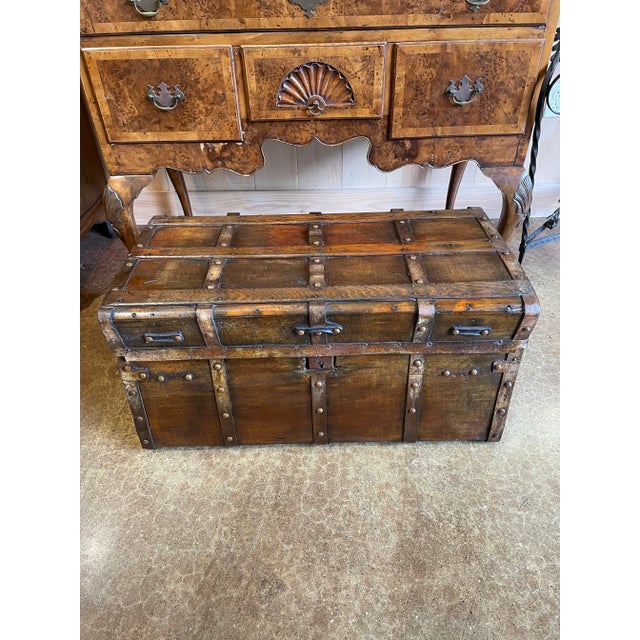 An authentic antique wooden travel trunk showcasing the craftsmanship and durability of a bygone era. Constructed from...