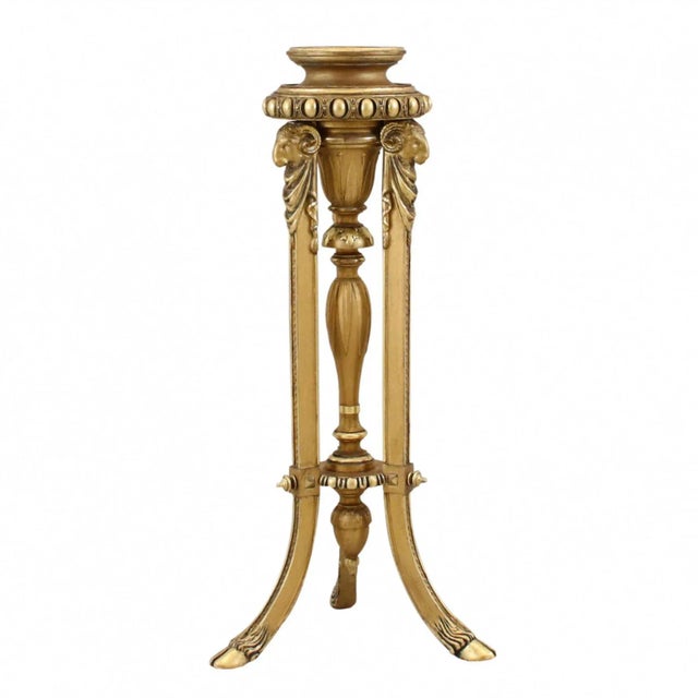 Console, pedestal of gilded wood in the Lous XVI style, stylized as an antique tripod with legs, with the heads of rams....