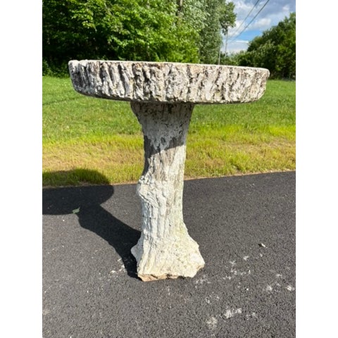 A single vintage faux bois concrete round bird bath with white painted finish.