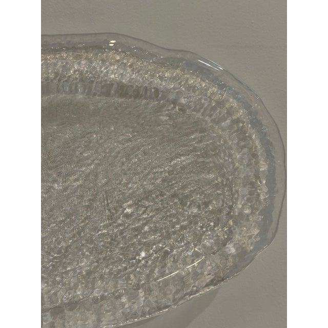 A textured glass oval platter featuring a distinctive melting ice aesthetic.