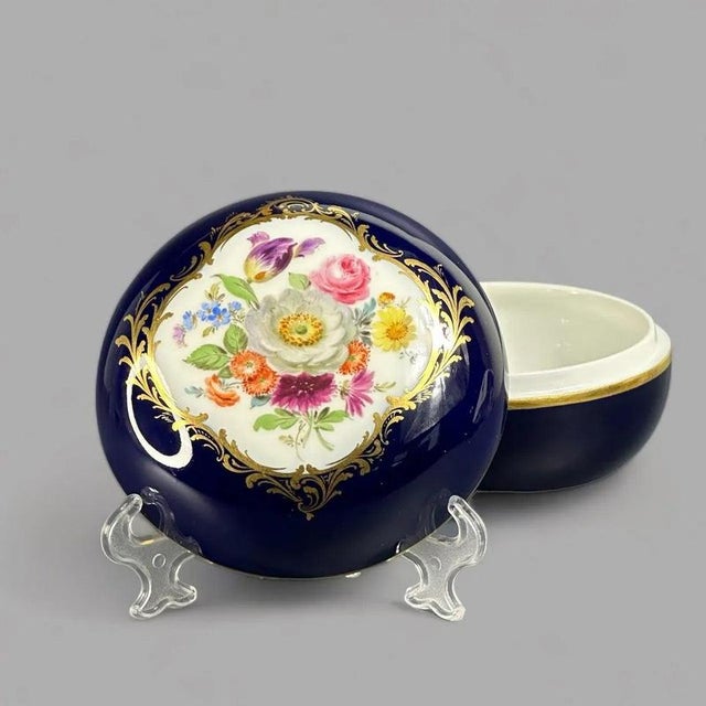 It is hand painted with a nice floral arrangement on white ground on the top of the lid with a fancy gold trim around the...