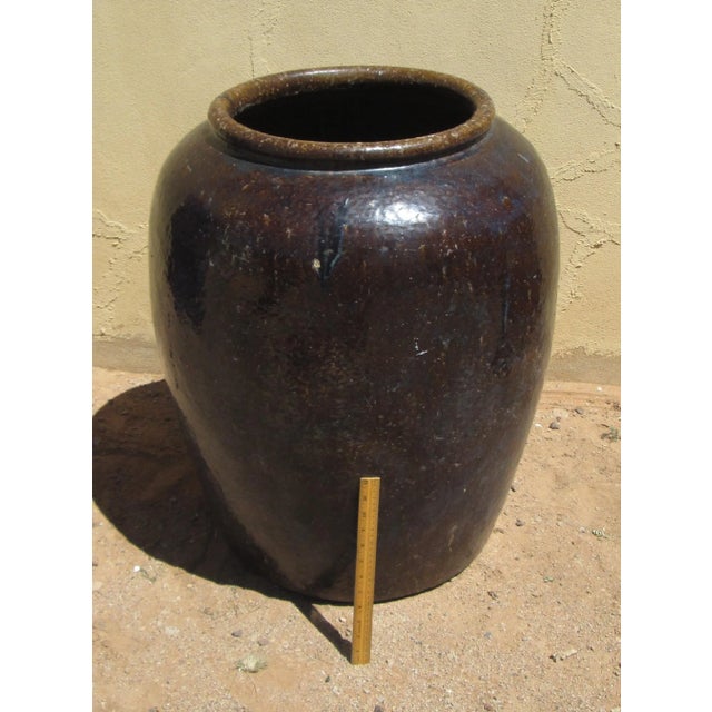 Antique South East Asian Wine Jar in a Dark brown glaze with hints of blue. The jar measures approximately 30 inches tall...