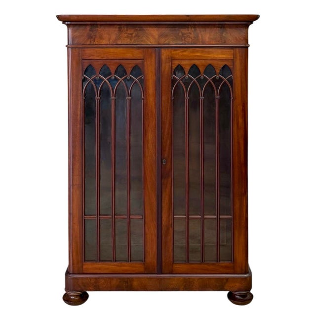 A fine Biedermeier bookcase in the Gothic taste, circa 1830. The case of oak construction clad in mahogany veneers. A...