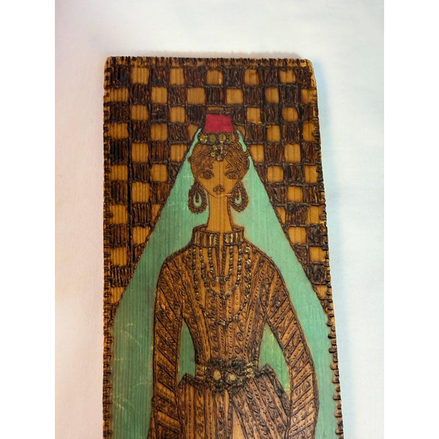 Pyrography on wood, freehand, depicting a woman in traditional late-Ottoman dress. Veiled beneath a crimson fez, robe and...