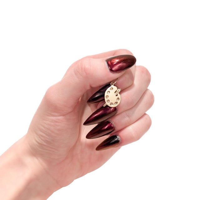 A fine vintage gold charm. In 14 karat yellow gold. In the form of an artist's palette with a trio of paintbrushes. With...