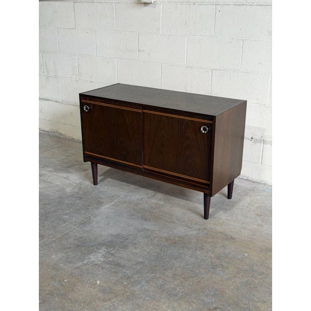 Beautiful vintage Danish modern cabinet crafted in stained oak, featuring elegant sliding doors, tapered legs, and refined...
