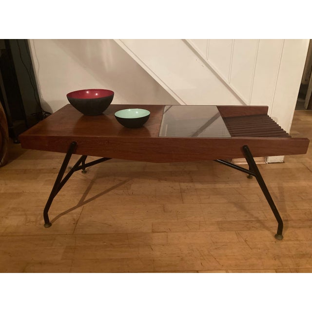 Beautifully designed side table. Italy, 1950s. Teak veneer, teak wood. Small, colorless glass top. Black lacquered metal...