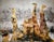 A gathering of figures fills this tall canvas in warm tones of rose and amber, built up over a ground of gold leaf that...