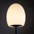 Floor lamp featuring an organically shaped, mushroom-like shade made of opaline white glass atop a tapered black lacquered...