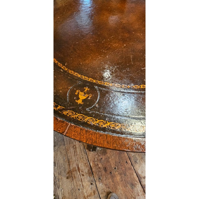 A nice drum table with Federal styling made of mahogany inset with a leather top. The leather top a gold floral trim on...
