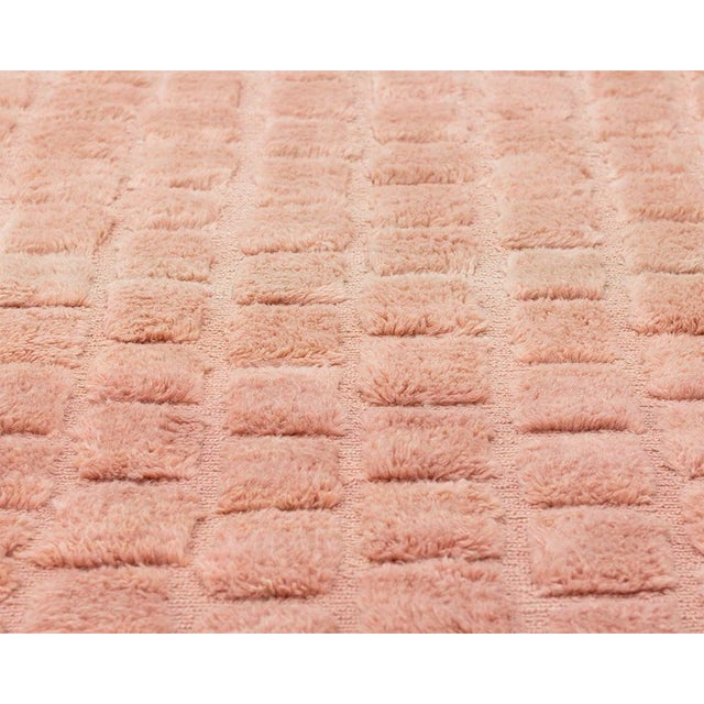 This hand-knotted wool rug in warm terracotta features a structured geometric square pattern with a subtle embossed...