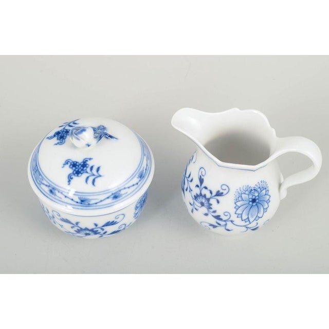 Meissen blue onion sugar bowl and creamer, mid-20th century. A set consisting of a classic lidded sugar bowl and a creamer...