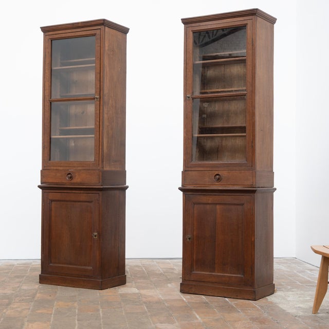 A beautiful pair of oak pharmacy display cabinets dating from the late 19th century, with slender and elegant proportions....