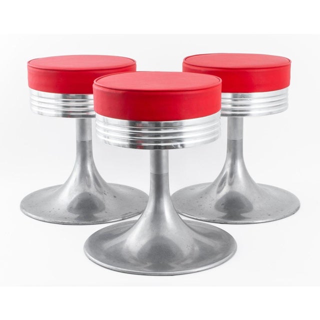 Set of Three American Industrial Modern Aluminum Stools, the seats upholstered in red faux leather, in the Art Deco taste....