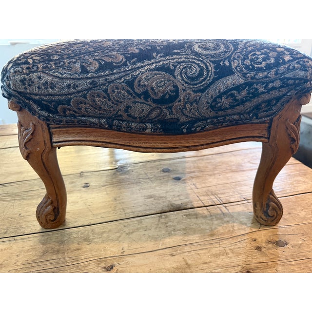 Charming antique French footstool featuring a beautifully carved hardwood frame with graceful cabriole legs, foliate and...