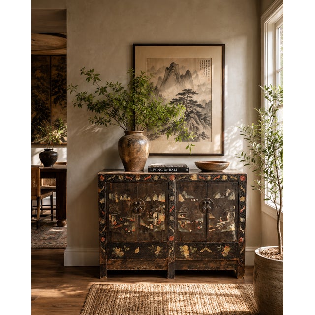 A striking early 20th-century Chinese hand-painted lacquer cabinet featuring an atmospheric landscape scene across both...
