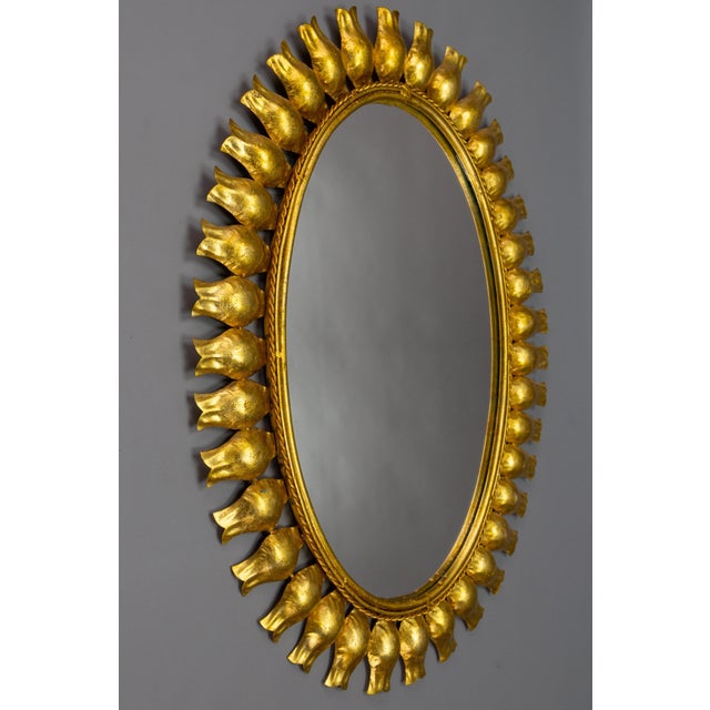 Mid-century gilt metal sunburst-shaped mirror, Germany, circa the 1950s. A beautiful Hollywood Regency-style oval sun- or...