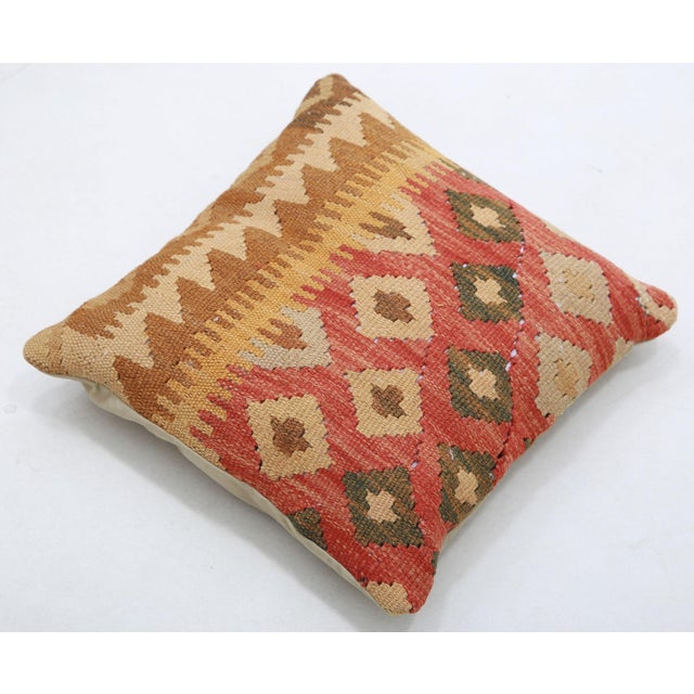 A one-of-a-kind handwoven Afghan wool kilim accent pillow featuring split design of gold stripes and a red diamond grid....