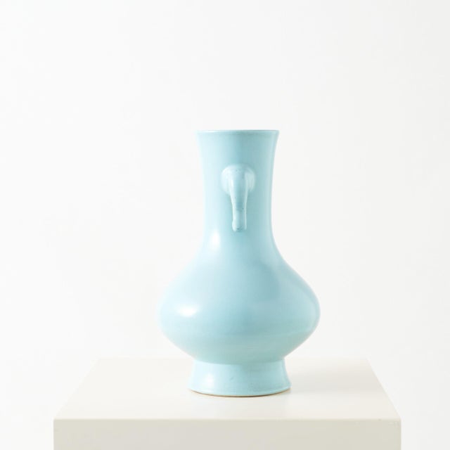 Pear-Shaped Cyan Glazed Vase with Elephant Handles A decorative pear-shaped vase featuring a soft, pale cyan glaze and...