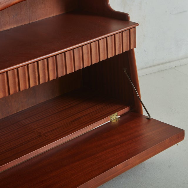 A stunning 1950s Italian secretary desk constructed with birch and walnut. This piece features a sculptural profile with a...