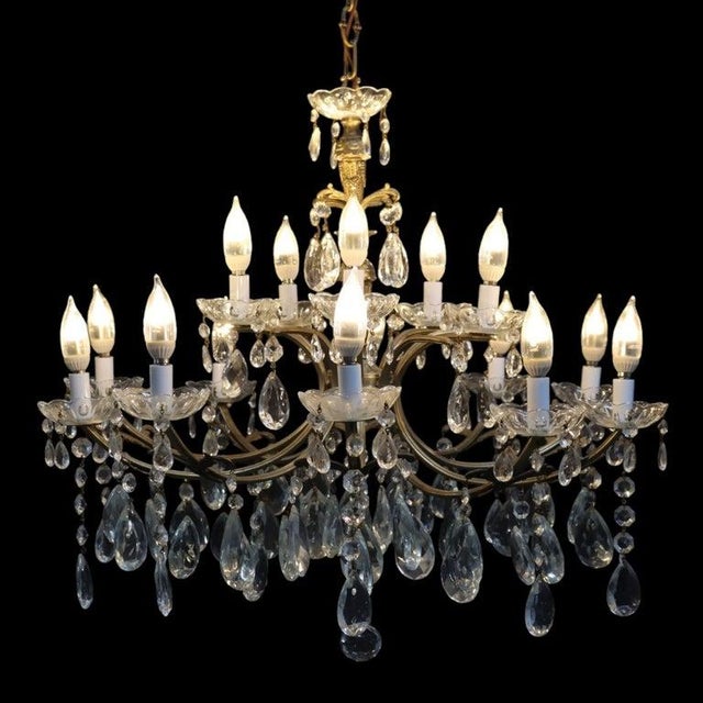 This vintage chandelier, dating to approximately 1940, features a gilt bronze frame adorned with numerous crystal prisms...
