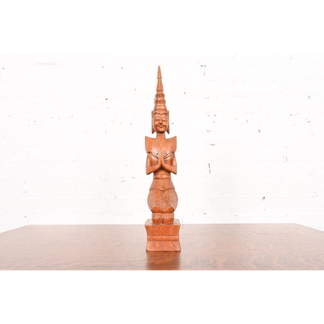A beautiful hand-carved solid teak Thai Theppanom sculpture or statue depicting a celestial being kneeling in prayer...