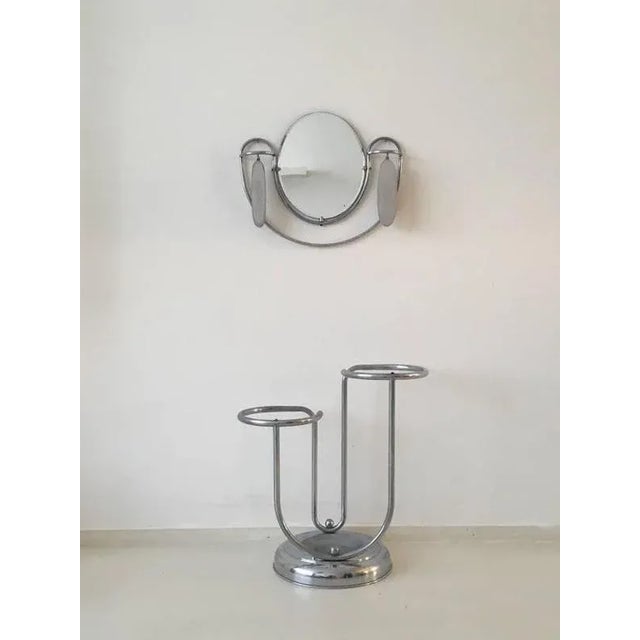 Art Deco set, consisting of a tubular chrome umbrella stand and a mirror with beveled glass and with two brushes. This set...