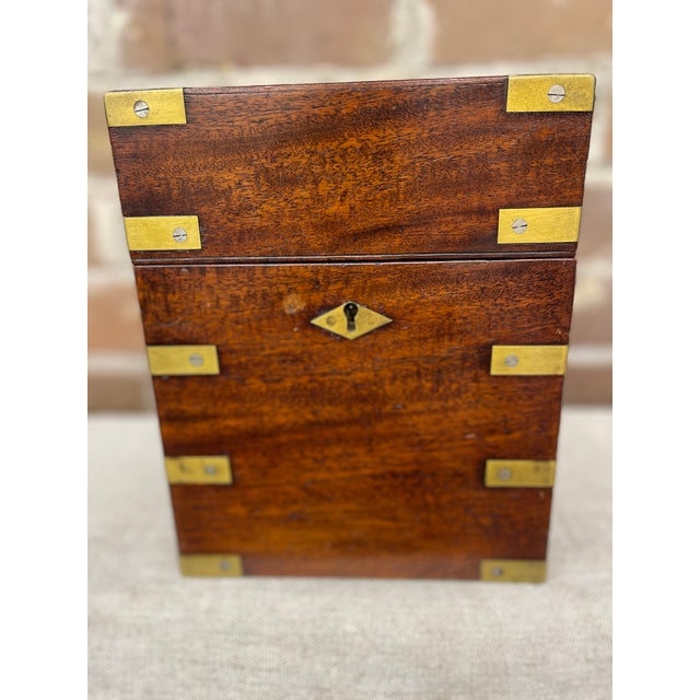 A 19th century English Mahogany box with brass strap work, flush side handles, and a divided green lined interior holding...