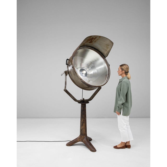 Oversized studio spotlight lamp on a tripod stand in Aged Brass and Bronze. Finished in aged brass and bronze, this...