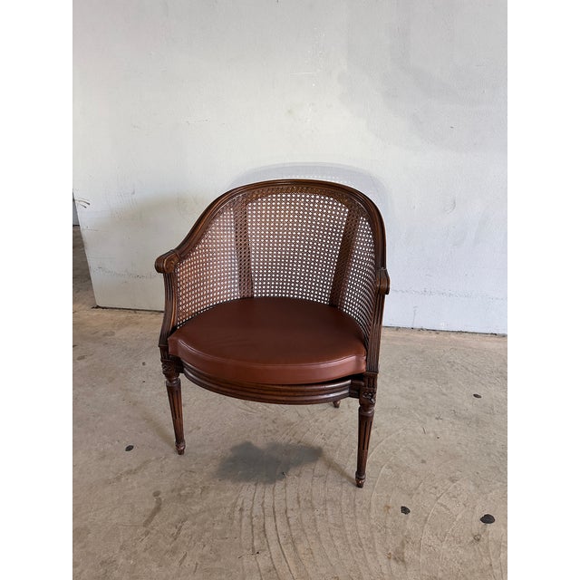 Charming French Louis XVI Style Cane Armchair, circa early 20th century. Features a hand-carved walnut frame with fluted...