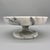 Solid marble pedestal dish carved from natural stone with soft gray veining throughout. The form is inspired by classical...