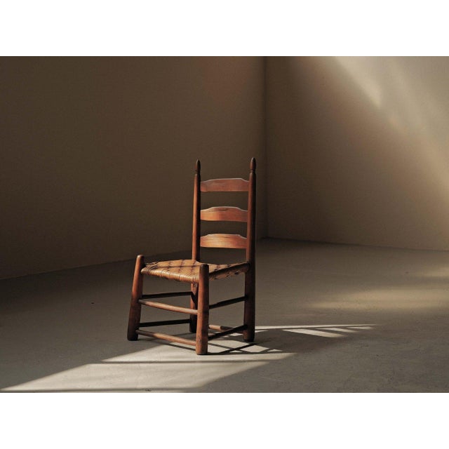 This low chair, crafted in the United States around 1900, features a turned solid wood structure typical of Shaker style...