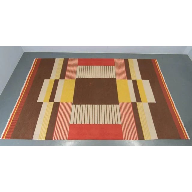 This stunning vintage rug by Antonin Kybal made in 1948 combines bold geometric patterns with a warm and inviting color...