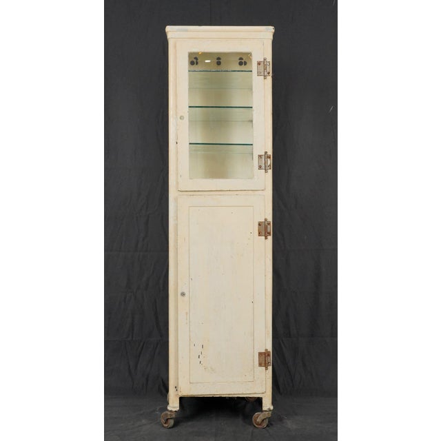 Mid Century tall and narrow steel medicine cabinet with two locking compartments. The upper compartment has a glass door...