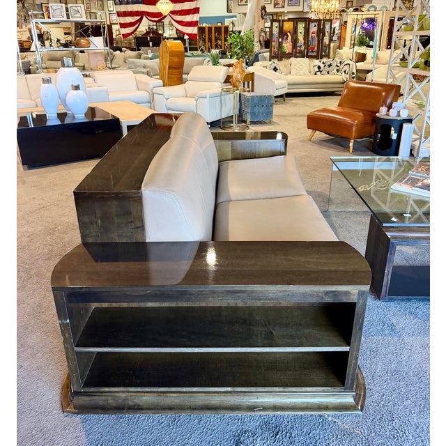 Distinctive sofa featuring a rich brown/tan leather seat and a dark wood frame, complemented by built-in shelving along...
