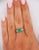 1.17 carat oval cut emerald ring, half bezel east west set with all natural mined gemstones. Adorned with 6 round cut...
