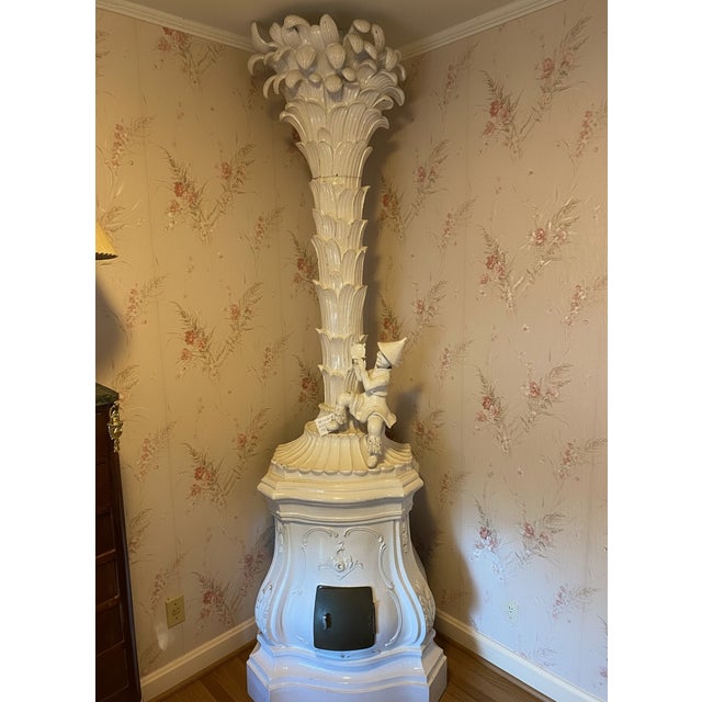 Antique Continental glazed terracotta stove in chinoiserie motifs. In off white glaze with frothy palm leaf finial at the...