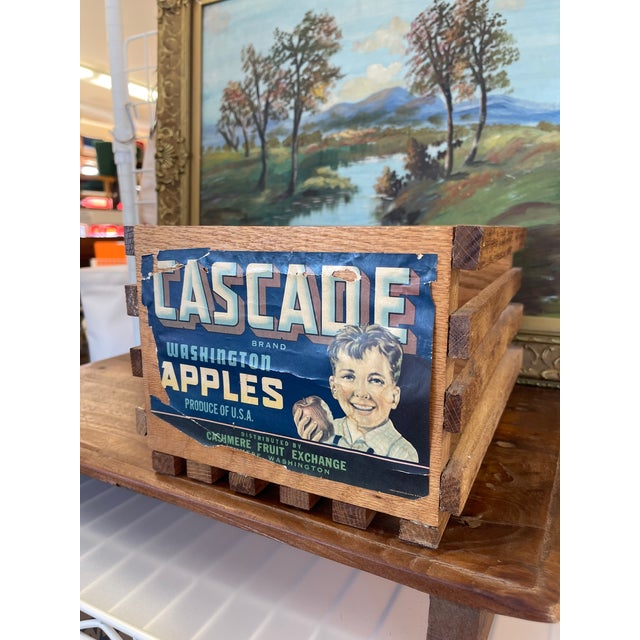 A vintage wooden fruit crate featuring the original "Cascade Brand Washington Apples" label, distributed by the Cashmere...