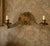 A striking vintage double wall sconce in aged brass, designed around a dramatic symmetrical composition. Two candle-style...