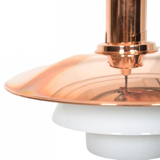 Poul Henningsen PH3½ / 3 pendant with a top shade of copper and a fitting of copper, and under shades of opal glass. The...