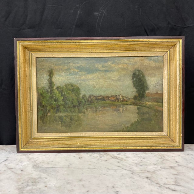 Atmospheric landscape painting by Mathieu Thirionet (1860–1937) depicting a tranquil waterside scene with distant...