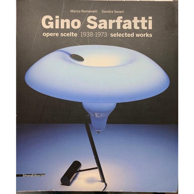 Model 565, a direct light table lamp designed in 1956, features a steel spring that supports the spotlight's reflector....