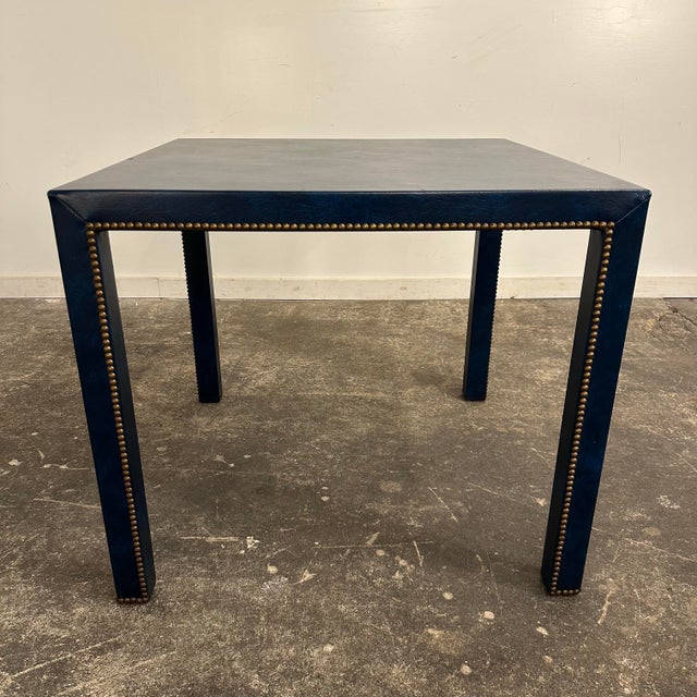 This is a Pierre Lottie’s-style dining table featuring brass stuffs and a dimensional blue vinyl that’s been wrapped...