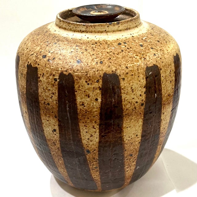 1970's hand-crafted stoneware studio pottery jar with lid. The tan salt glazed body is decorated with vertical brown...