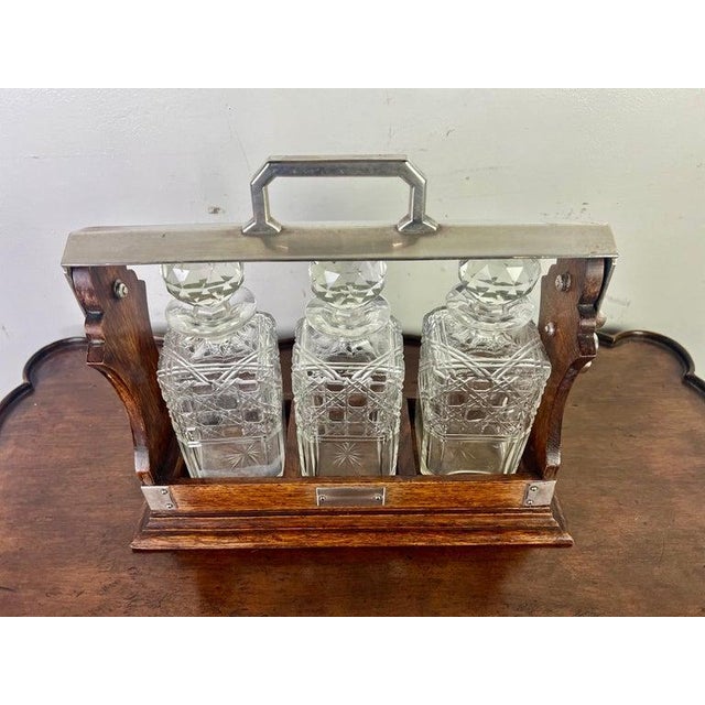 19th C. English decanter set housed in a wooden and metal-framed caddy. There are three crystal decanters with intricate...